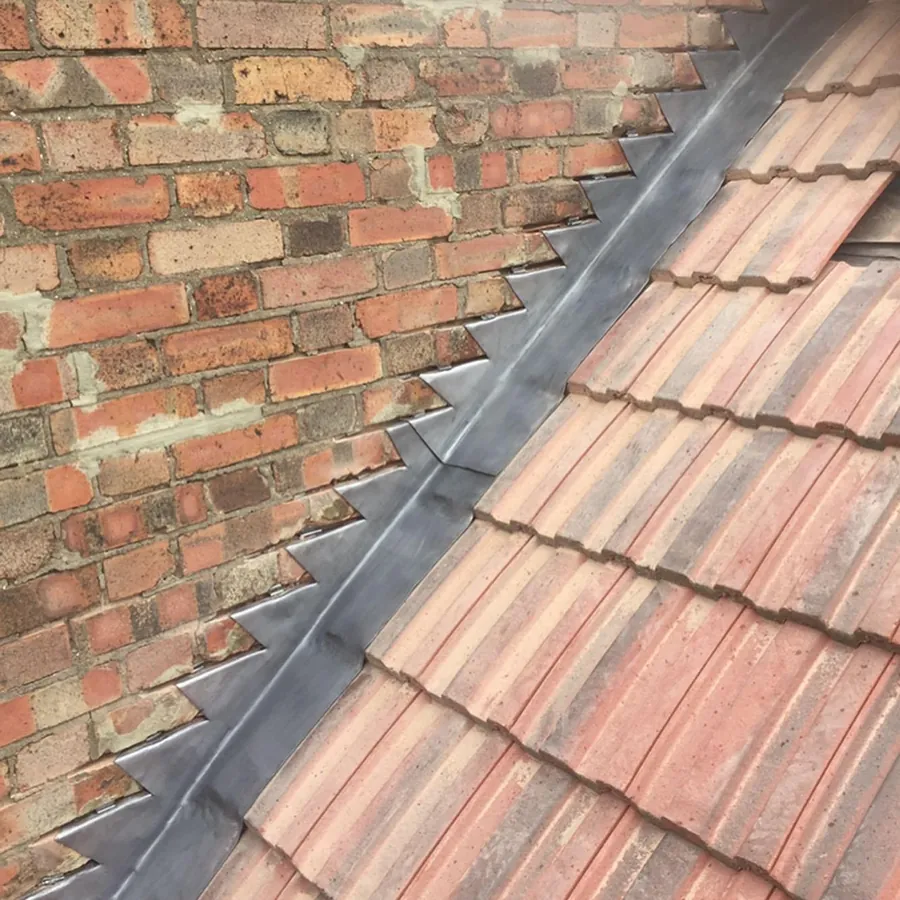 Lead step flashing where the tiles meet a brick wall