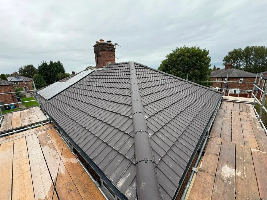 New grey tile hip roof with a chimney stack, seen from the scaffold