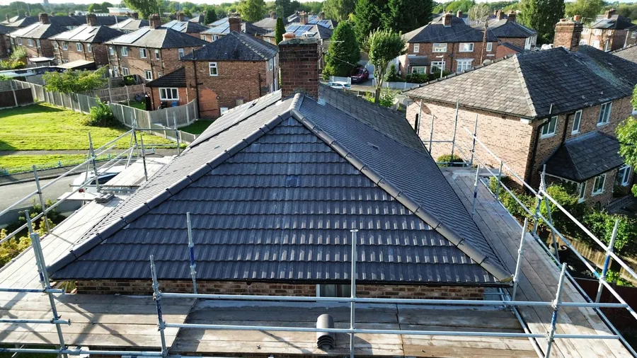 Finished grey tile hip roof seen from height over a north Manchester street