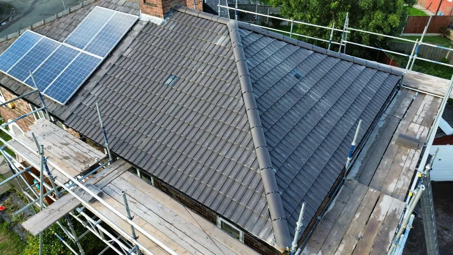 New grey hip roof next to a roof with solar panels