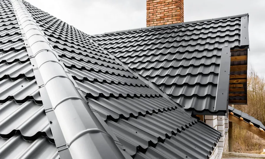 Grey interlocking tiles with a new ridge and valley by a chimney