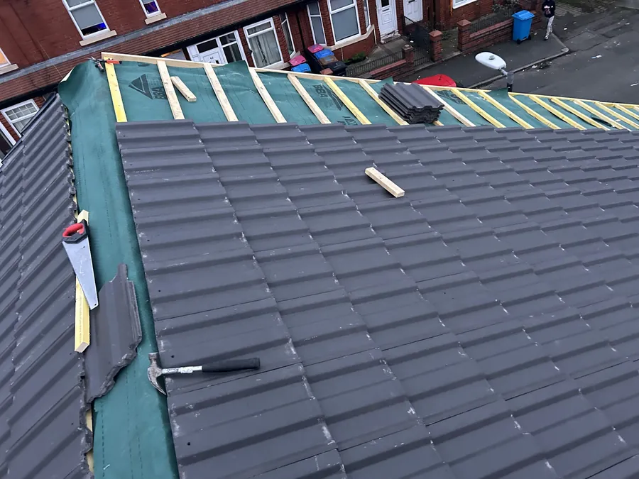 Grey tiles being laid over membrane on a terraced house