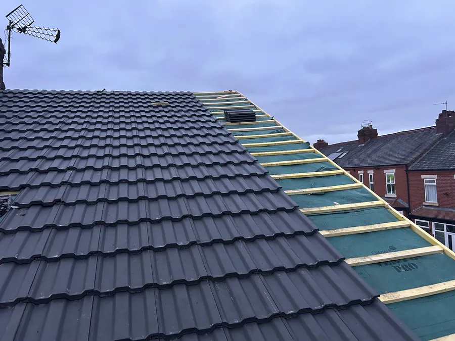 Dark interlocking tiles half laid with battens showing above