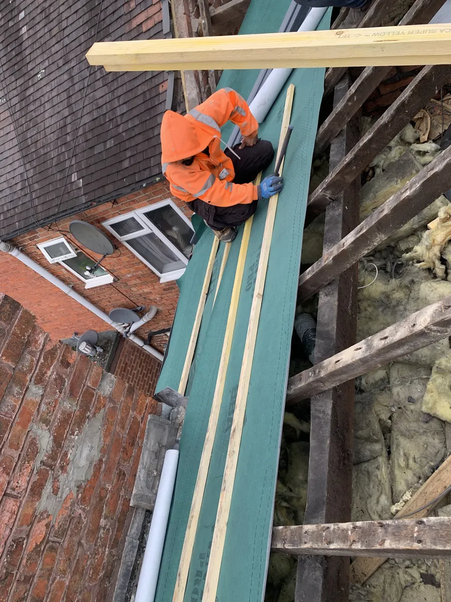 Roofer fixing battens over green membrane on a terrace roof