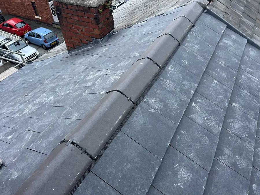 Grey slate roof with ridge tiles and a brick chimney